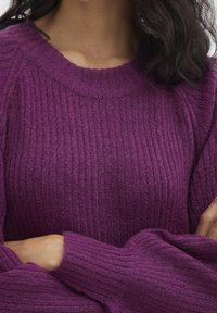 Pullover a coste viola con collo rotondo e maniche ampie, caratterizzato da una texture morbida e una vestibilità morbida.