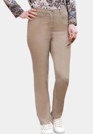 Beige Jeans mit geradem Bein, ausgestattet mit Taschen, einem Knopfverschluss und kombiniert mit weißen Sneakers.