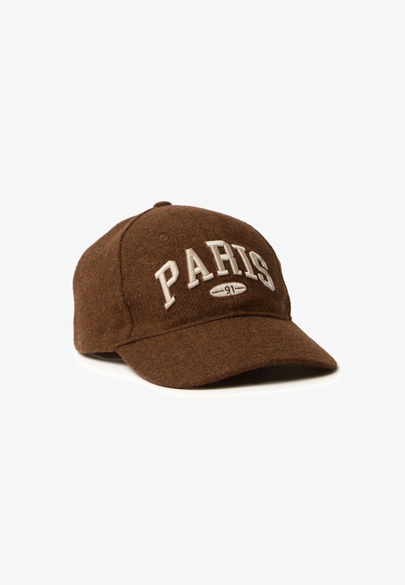 Bruine wollen baseballpet met witte "PARIS" letters en borduursel van 91 aan de voorkant. Heeft een gebogen rand en een verstelbare strap aan de achterkant.