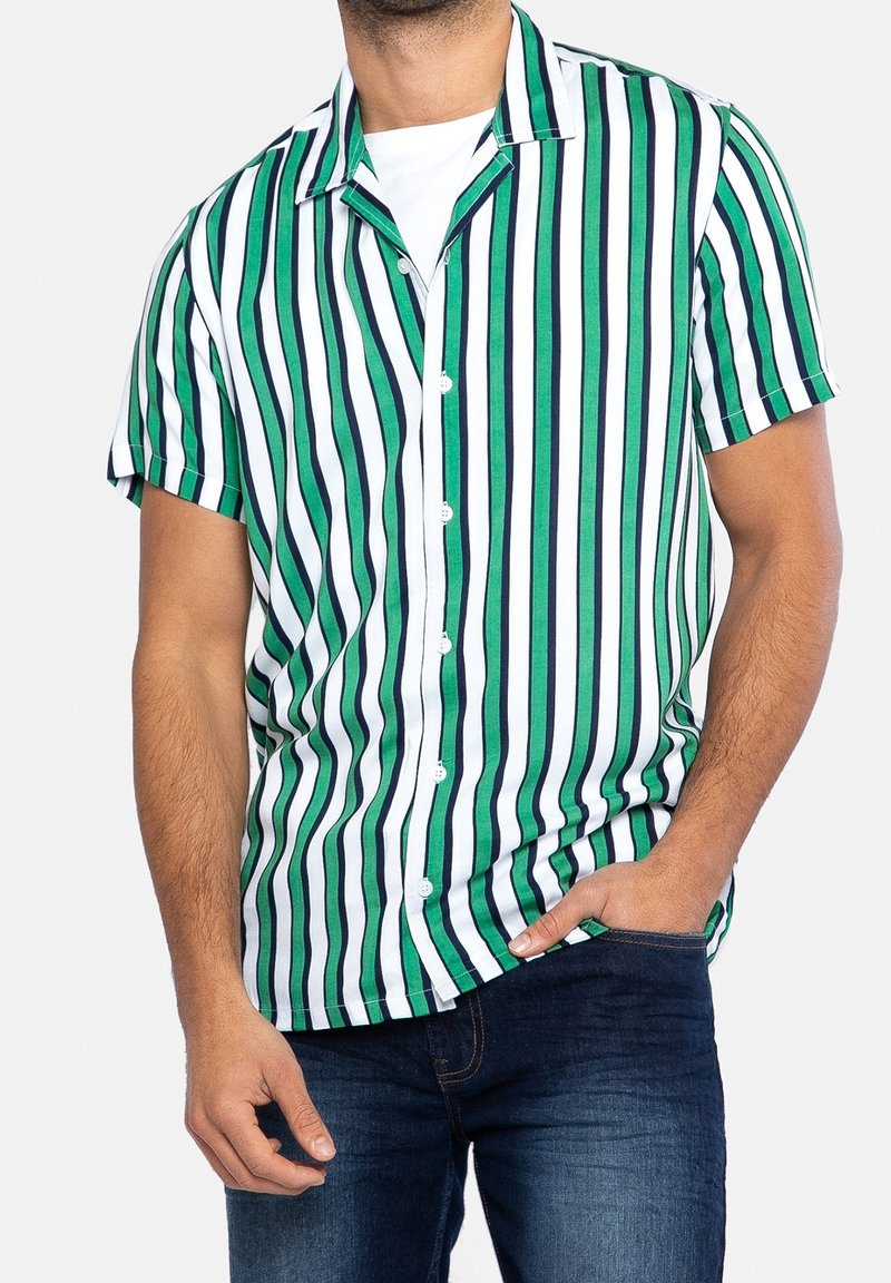 Camicia a maniche corte con bottoni, caratterizzata da righe verticali verdi e bianche, con colletto a camicia, tessuto morbido e vestibilità rilassata. Indossati jeans in denim.