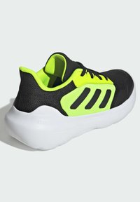 Black athletic shoe with neon yellow accents, mesh upper, thick white sole, and distinctive black stripe design on the side.