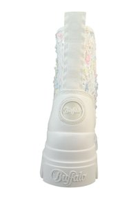 Botă înaltă albă cu un exterior din dantelă texturată, având accente florale multicolore, un logo rotund aproape de călcâi și o talpă groasă.