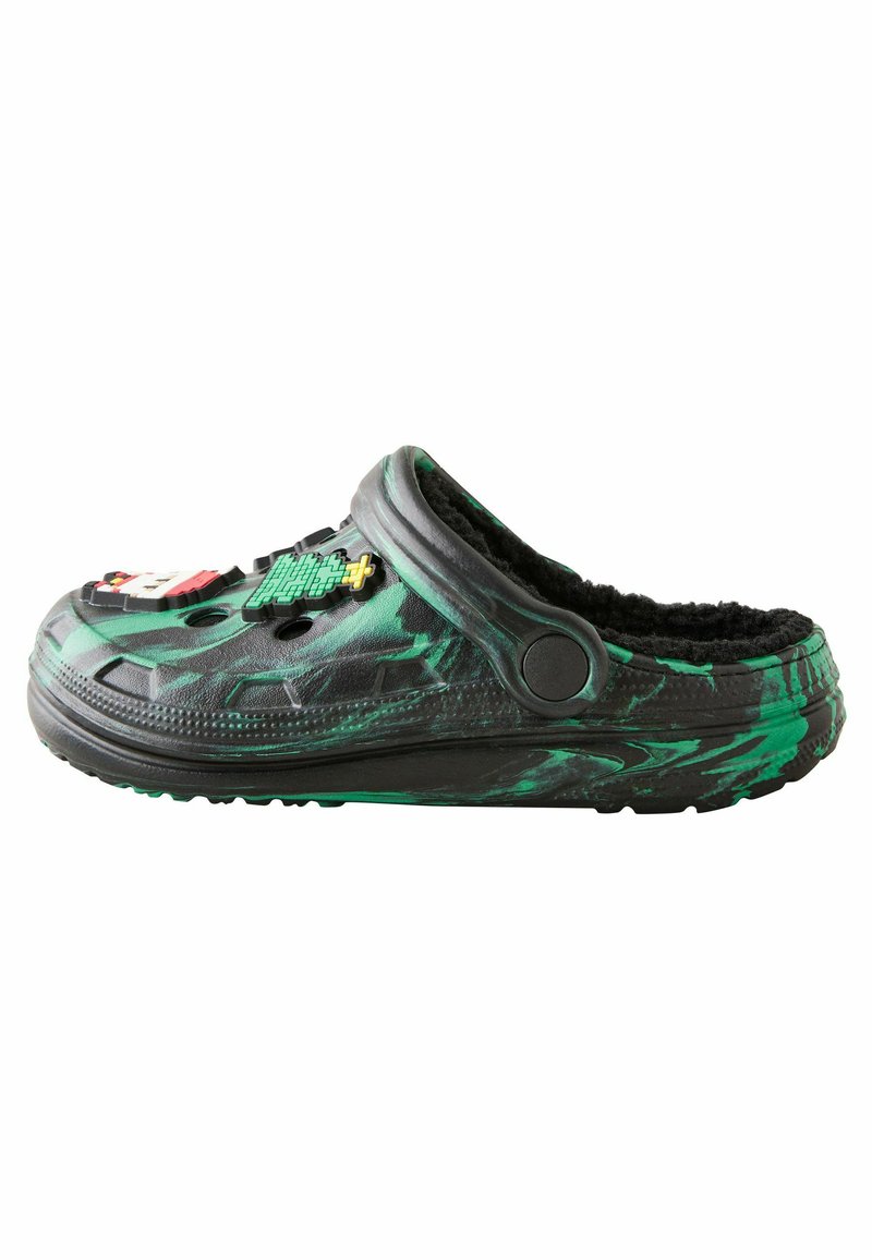 Sabot negru și verde cu un model, cu un interior pufos, având multiple insigne decorative, formă rotundă și două orificii de ventilare.
