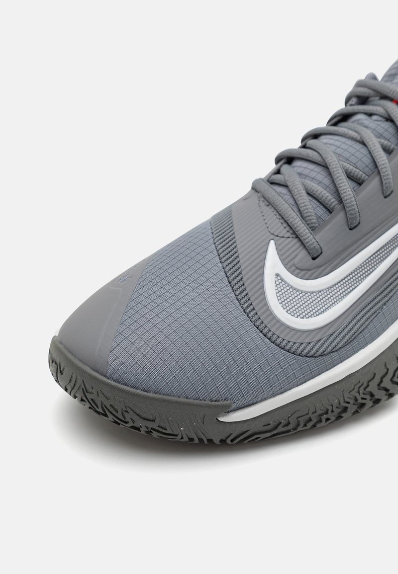 Chaussure de sport grise avec un dessus texturé, dotée d'un logo Swoosh blanc, d'une semelle en caoutchouc avec un motif de traction et de lacets assortis en gris.