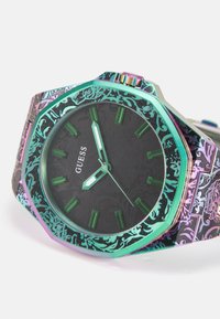 Montre à cadran noir avec boîtier octogonal, marqueurs d'heure verts et bracelet multicolore à motif. Présente un design floral stylisé et des accents métalliques.