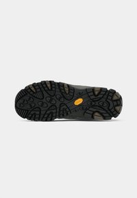 Black rubber shoe sole with textured grip patterns, featuring a Vibram logo in yellow and brown accent details.