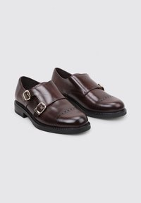 Zapatos de cuero marrón con doble hebilla, punta redondeada, costura decorativa en la parte delantera y un bajo tacón de goma negra.