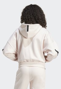 Lichtroze hoodie met een relaxte fit, verstelbare capuchon en geribde manchetten. Bevat zwarte accentstrepen op de mouwen en een label op de achterkant.