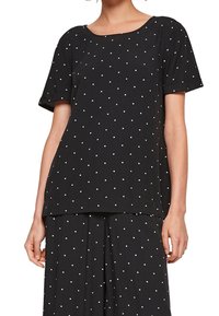 Haut noir à manches courtes avec des pois blancs, encolure ronde, coupe ample, tissu doux et ourlet droit. Convient pour une tenue décontractée.