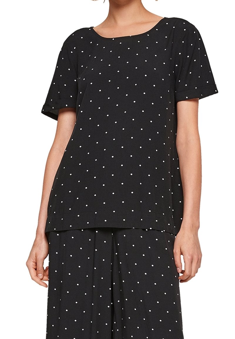 Haut noir à manches courtes avec des pois blancs, encolure ronde, coupe ample, tissu doux et ourlet droit. Convient pour une tenue décontractée.