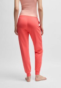 Koraal joggers van zachte stof, met een elastische tailleband en geribbelde cuffs, ontworpen voor comfort en casual gebruik.