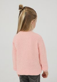 Maglione lavorato a maglia rosa chiaro con un design testurizzato e spesso, e maniche lunghe. Presenta un collo rotondo e finiture a costine su orlo e polsini.