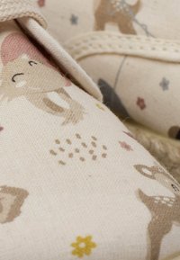 Scarpe in tela con uno sfondo beige chiaro, che presenta motivi illustrati di animali e fiori in tonalità tenui di marroni, rosa e gialli.