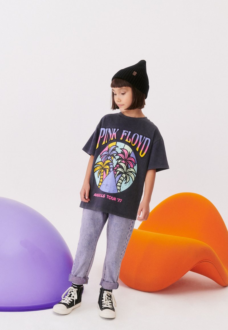Grafična majica s kratkimi rokavi v antracitno sivi barvi z napisom "PINK FLOYD" in obliko palme, v kombinaciji z svetloberimi jeans hlačami in črnimi supergami.