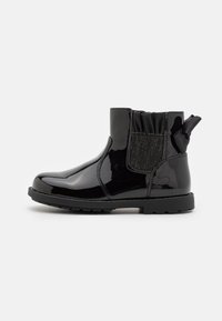 Bottines en cuir noir verni avec fermeture éclair, panneau latéral élastique et un accent en tissu texturé avec un nœud au talon. Semelle en caoutchouc.