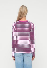 Långärmad topp med horisontella ränder i rosa och vitt, och en enfärgad rosa krage. Tillverkad av ett mjukt, stretchigt material.