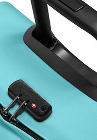 Hartschalenkoffer in Türkis mit strukturierter Oberfläche. Verfügt über einen schwarzen Verschlussmechanismus und einen ausziehbaren Griff. Reißverschlussöffnung.