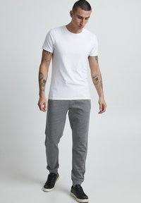 White cotton T-shirt paired with gray jogger pants. The joggers feature a slim fit, elastic waistband, and side pockets. Finished with black sneakers.