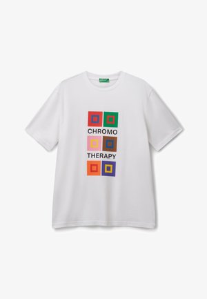 Camiseta blanca con seis diseños cuadrados coloridos y las palabras "TERAPIA DE COLOR" impresas en negro en el centro frontal.