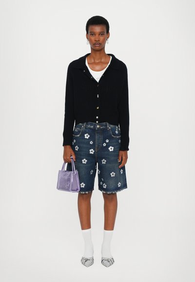 Cárdigan de canalé negro, camiseta blanca, pantalones cortos de mezclilla con patrones florales plateados, bolso mini morado, calcetines blancos y tacones a rayas.