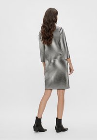 Mekko, jossa on mustavalkoiset raidat, kolmen neljänneksen hihat, suora leikkaus ja takana halkio. Yhdistetty mustiin nilkkabootseihin.