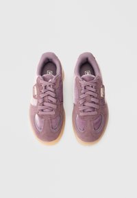 Μοβ σουέντ αθλητικά παπούτσια με υφή, δέσιμο με κορδόνια και σόλα από καουτσούκ. Διαθέτουν ετικέτα με λογότυπο στο πλάι και στρογγυλεμένη μύτη.