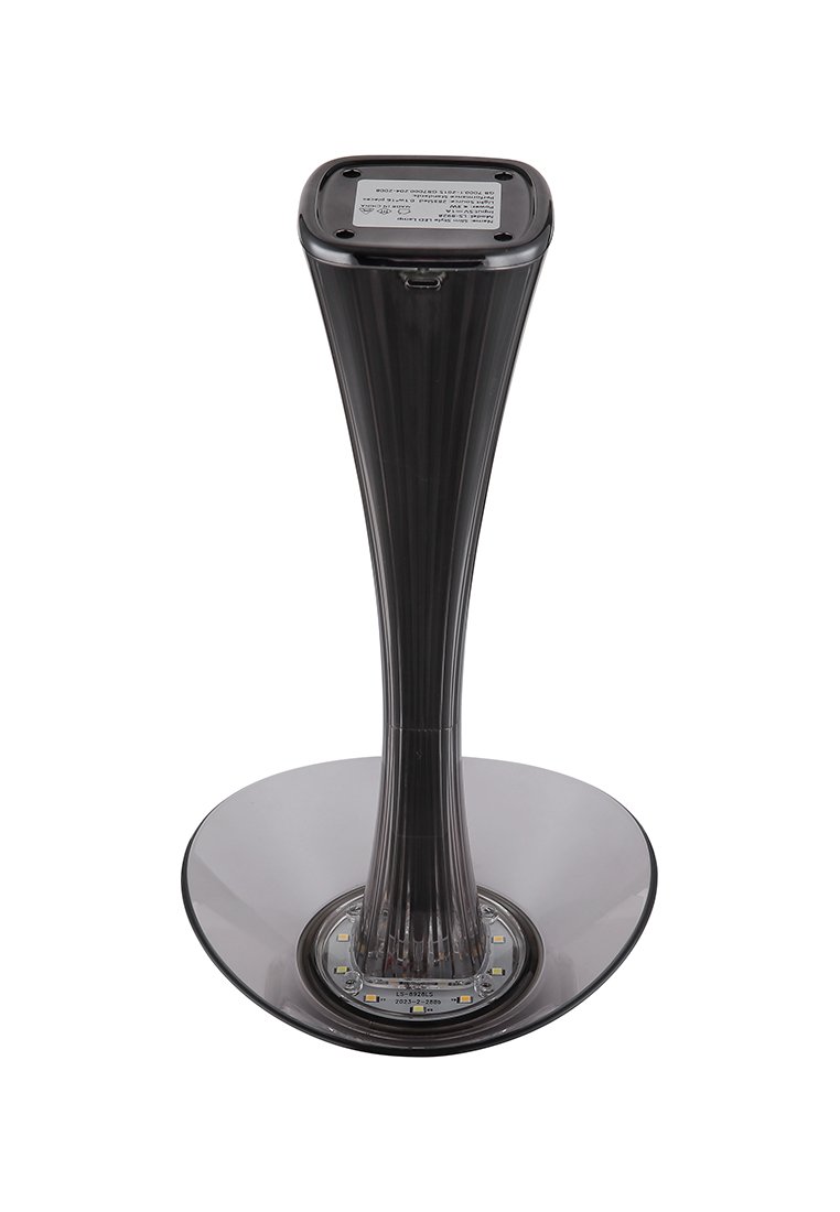 Průhledná černá plastová stolní lampa s kuželovitým designem a širokým kulatým podstavcem, opatřená LED světly na spodní straně a čtvercovou horní částí.