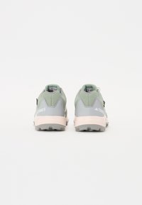 Chaussures de trail grises et vert menthe avec une tige texturée, une semelle amortie et des accents blancs. Elles comportent une languette et un relief rugueux pour une meilleure traction.