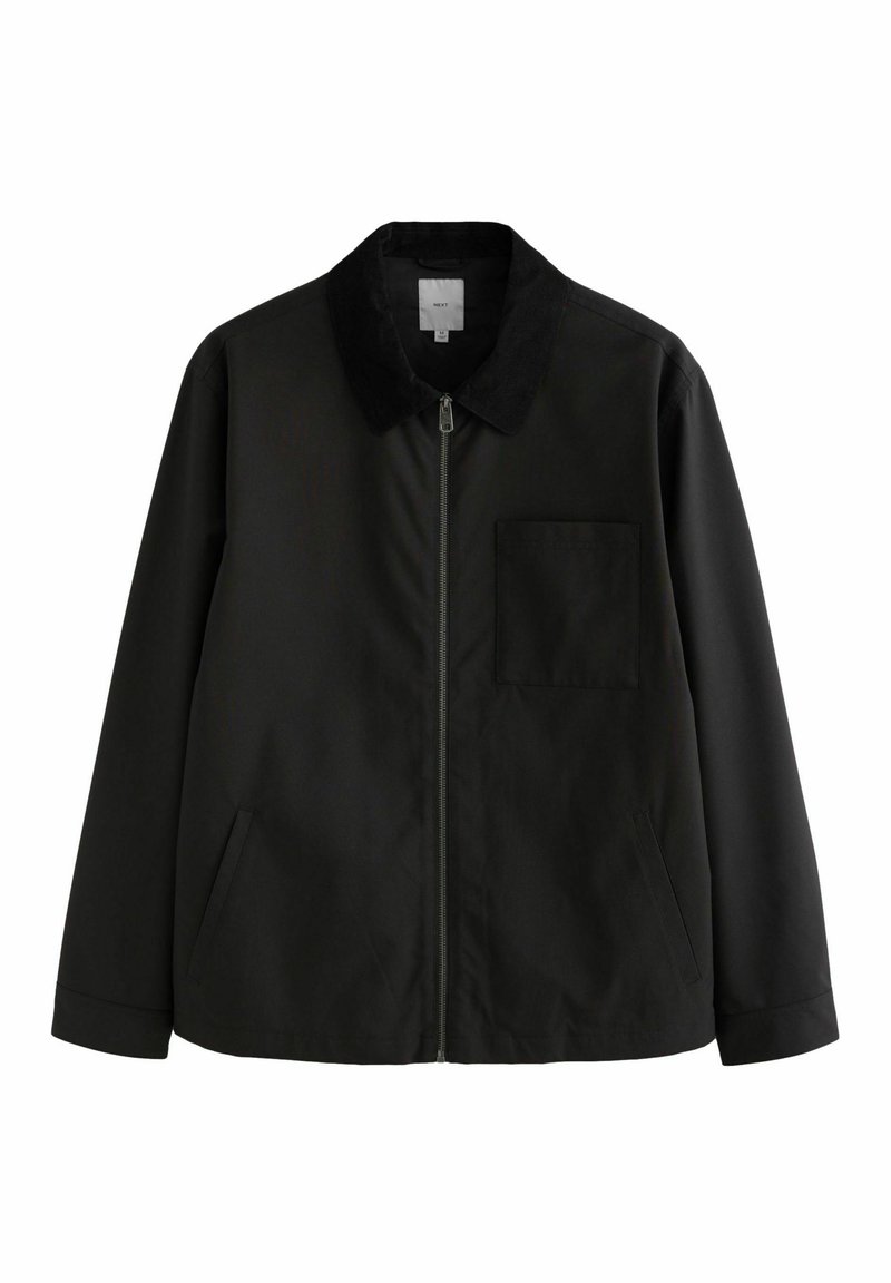 Chaqueta negra de tejido suave, con cierre de cremallera, un cuello suave de contraste y un bolsillo en el pecho. Tiene bolsillos laterales y un corte relajado.