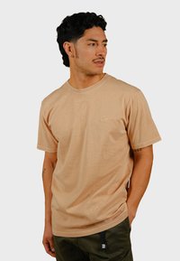 Beige katoenen t-shirt met korte mouwen, een ronde hals en subtiel olifantenlogo op de borst; gladde textuur, relaxte pasvorm.