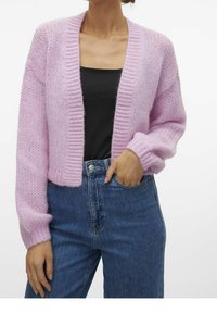 Cardigan a maglia rosa chiaro con una vestibilità comoda, bordi a coste e maniche lunghe, abbinato a jeans a vita alta blu scuro.