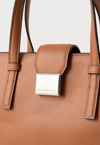 Brown leather handbag with rectangular shape. Features a smooth texture, dual handles, and a metal clasp with "KARL LAGERFELD" engraving.