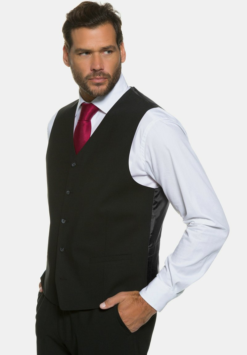 Schwarze Weste mit glatter Textur, ausgestattet mit einem Frontverschluss mit sechs Knöpfen, mit notched Revers und seitlichen Taschen, getragen über einem weißen Hemd.