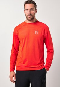 Pitkähihainen, kirkkaanpunainen urheilupaita pyöreällä kaula-aukolla, valmistettu pehmeästä, kevyestä kankaasta. Rintamuksessa logo.