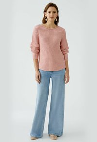 Hellrosa geripptes Sweatshirt mit langen Ärmeln, kombiniert mit hoch taillierten hellblauen weit geschnittenen Jeans und beigen Slippern.