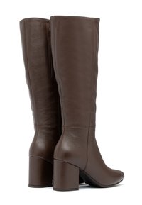 Para wysokich brązowych skórzanych kozaków na obcasie, z przeszyciami i gładkim wykończeniem, widzianych z tyłu i z boku.