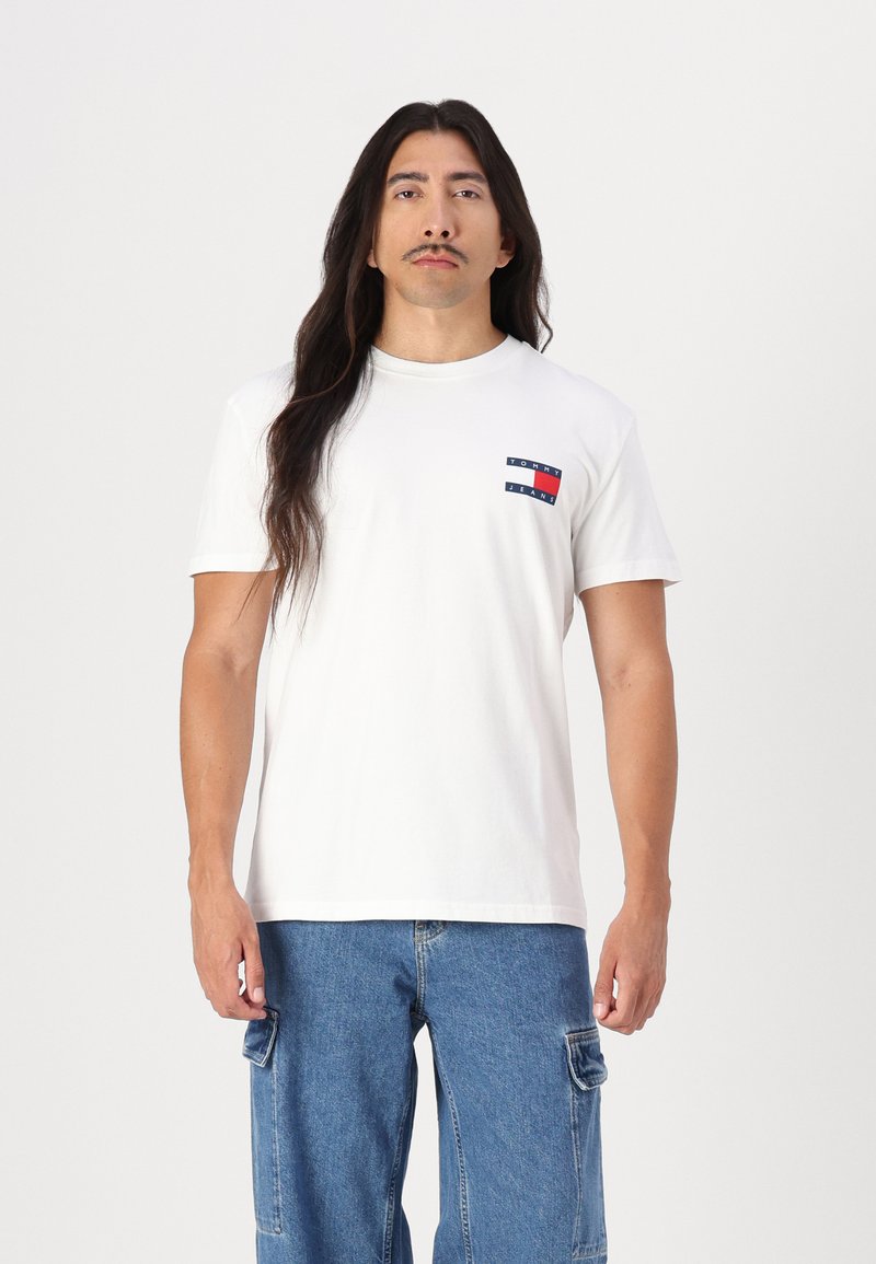 Hvit bomull t-skjorte med korte ermer, med en liten rød, hvit og blå logo på venstre bryst og en klassisk rund hals-design.