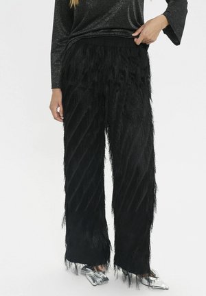 Schwarze Fransenhose mit diagonalen strukturierten Streifen, aus weichem Material gefertigt. Verfügt über eine entspannte Passform und einen elastischen Bund.