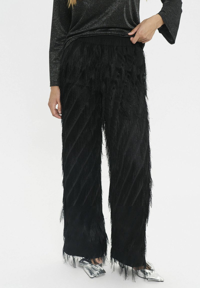 Schwarze Fransenhose mit diagonalen strukturierten Streifen, aus weichem Material gefertigt. Verfügt über eine entspannte Passform und einen elastischen Bund.