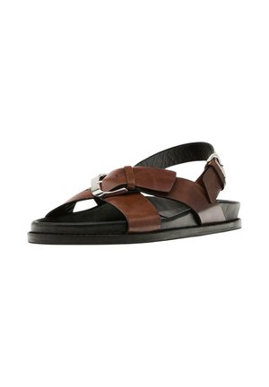 Sandali in pelle marrone con accenti neri, dotati di un design a fascia incrociata, fibbia alla caviglia regolabile e suola piatta per un'indossabilità facile.