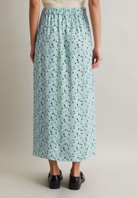 Jupe maxi légère imprimée florale en bleu clair avec taille élastique ; présente des motifs noirs, verts et roses sur un tissu doux et léger.