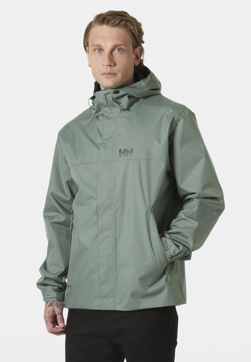 Chaqueta impermeable de color verde claro con capucha, bolsillos con cremallera, puños elásticos y un logo en el pecho. Textura suave, diseño moderno.