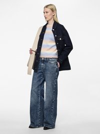 Jeans jakna v temno modri barvi z srebrnimi gumbi; pastelno črtast pulover; svetlo modri široki kavbojke; črne gležnjarje; svetlo bež torbica.