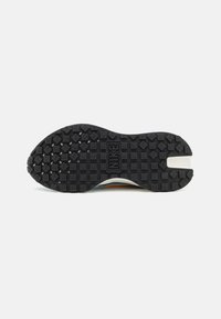 Nike sneaker outsole featuring a black rubber design with square and diamond patterns, highlighted by a white side accent and logo.