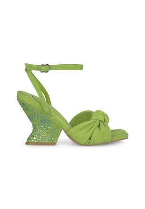 Sandale compensée en daim vert avec une sangle avant nouée, une sangle à la cheville avec boucle et un talon texturé orné de bijoux.