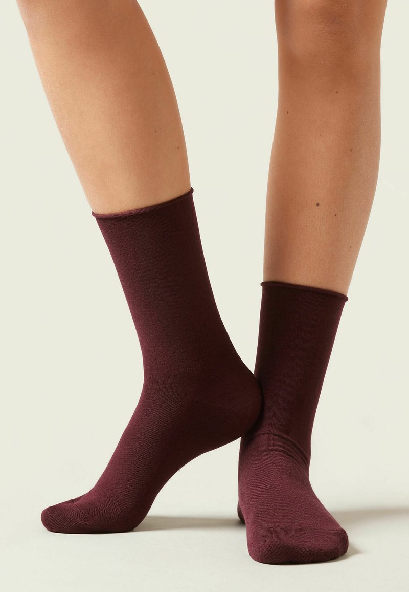 Burgundowe skarpetki kostkowe o gładkiej fakturze i żebrowanych mankietach, zaprojektowane tak, aby idealnie przylegały do kostki i połowy łydki.
