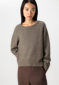 Maglione in lana marrone con vestibilità comoda, scollo rotondo e orlo a coste. Le maniche lunghe presentano una leggera sagomatura. Lavorazione a maglia morbida e testurizzata.