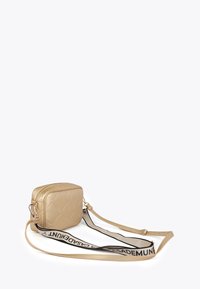 Borsa a tracolla oro trapuntata con una lunga tracolla, che mostra una superficie texture e un dettaglio del nome del marchio nero sulla tracolla.