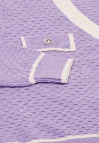 Levandulový pletený kardigan s texturovaným vzorem, krémovým lemem a dekorativním kamínkem na levém manžetu.