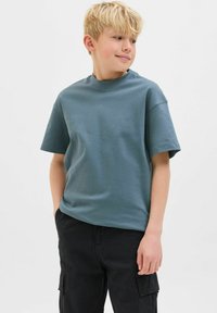 T-shirt a maniche corte di un colore teal tenue, realizzato in tessuto morbido. Design a girocollo con una vestibilità comoda, abbinato a pantaloni cargo neri.